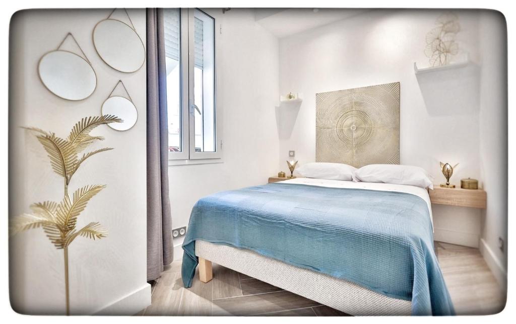 a white bedroom with a bed with a blue blanket at Le Vallaya Suites & Spa in Menton