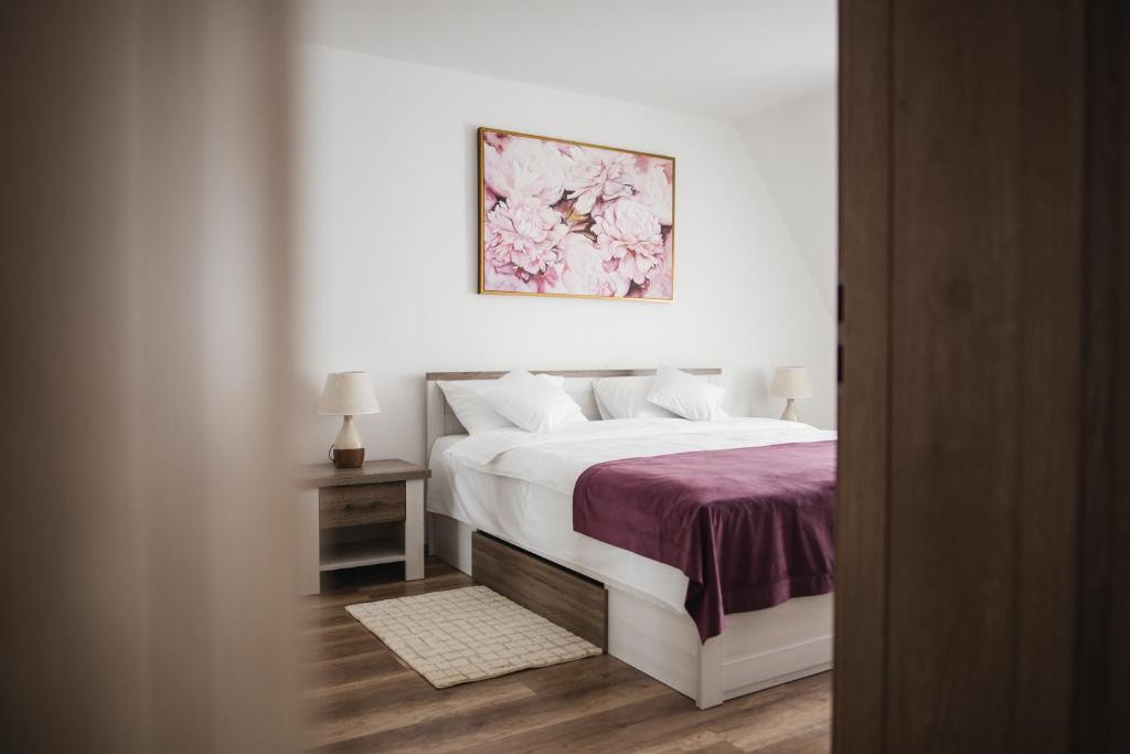 1 dormitorio con 1 cama blanca con manta morada en Vila Helena, en Sibiu