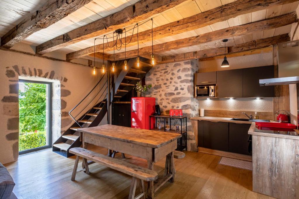 una cocina con una mesa de madera y una escalera en Maison typique des monts du Cantal, en Marmanhac