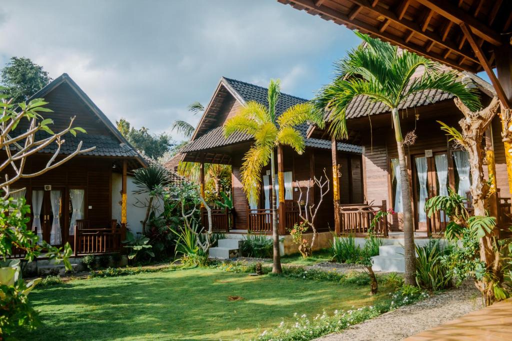 a house with palm trees in front of it at Kurnia Guest House & Spa in Nusa Penida