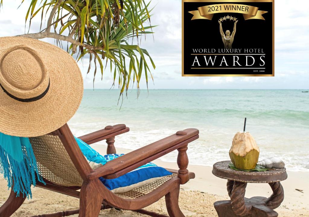 un sombrero de paja sentado en una silla en la playa en Tikitam Palms Boutique Hotel, en Pongwe