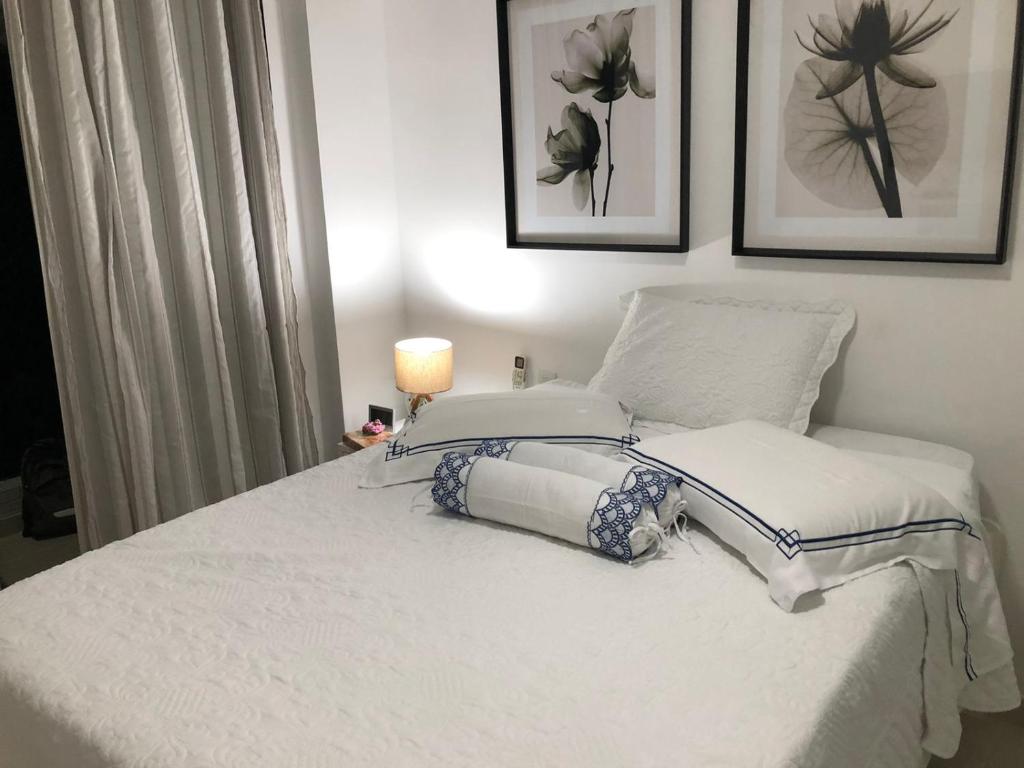 Una cama blanca con dos almohadas encima. en Conforto E Localizacao, en Salvador