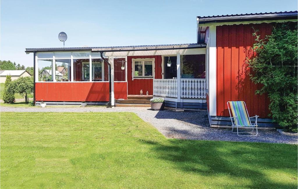 a red house with a chair in a yard at Amazing Home In Sffle With Kitchen in Säffle