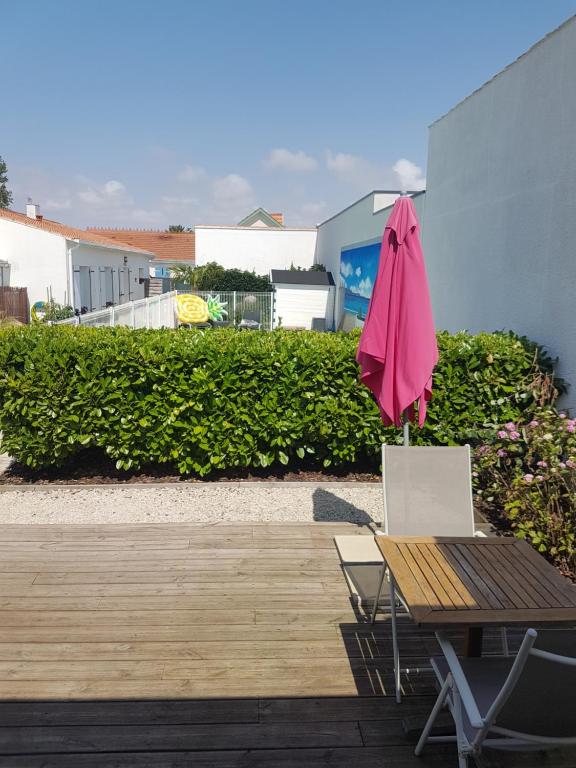 a pink umbrella sitting on a table and a chair at Appartement Ré (4 personnes) in Châtelaillon-Plage