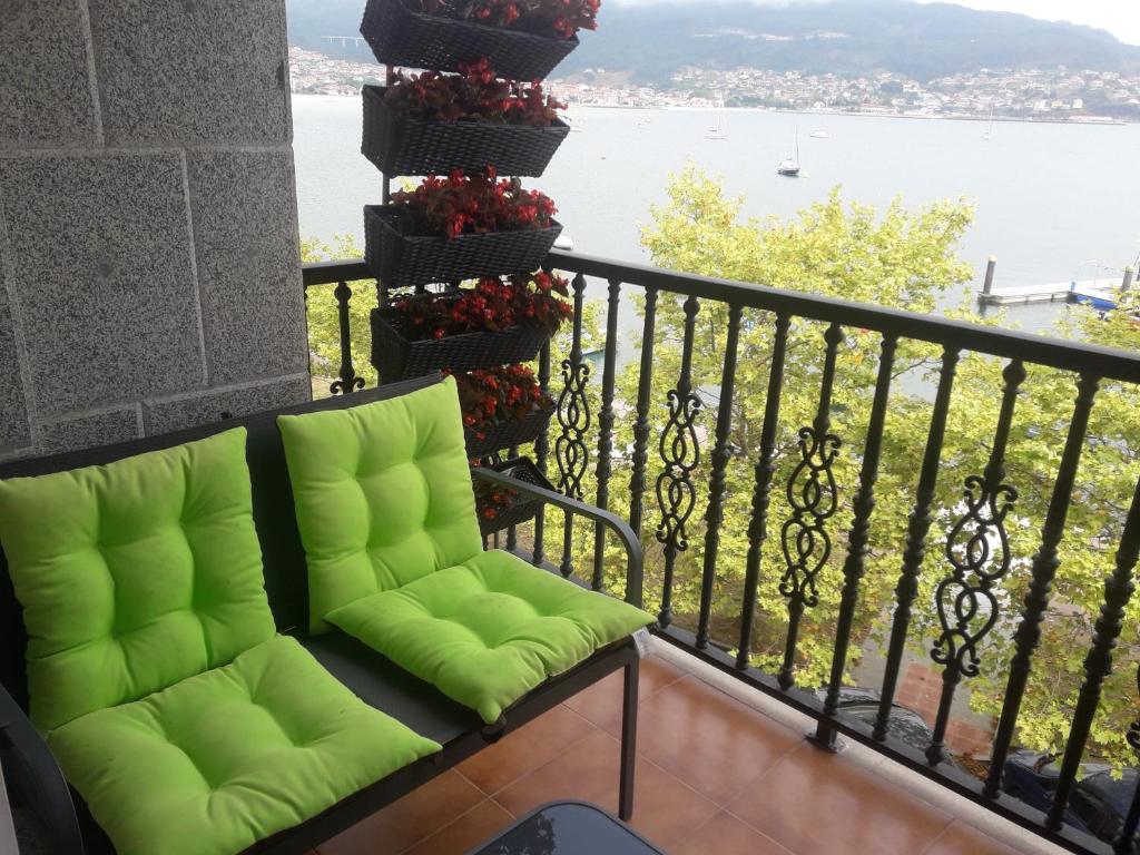 einen grünen Stuhl auf einem Balkon mit Blick auf das Wasser in der Unterkunft MAR AVILLA ESPECTACULAR RIA DE VIGO con PARKING PLAYA in Moaña