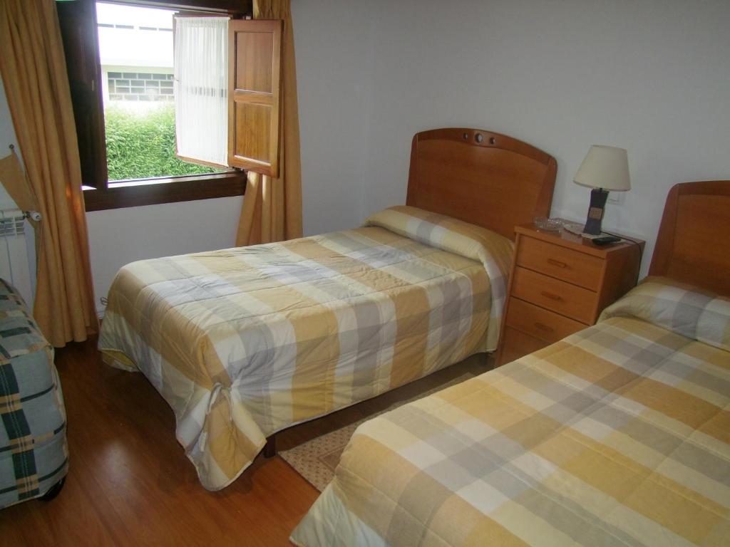 a hotel room with two beds and a window at Pension Gades in Cabezón de la Sal