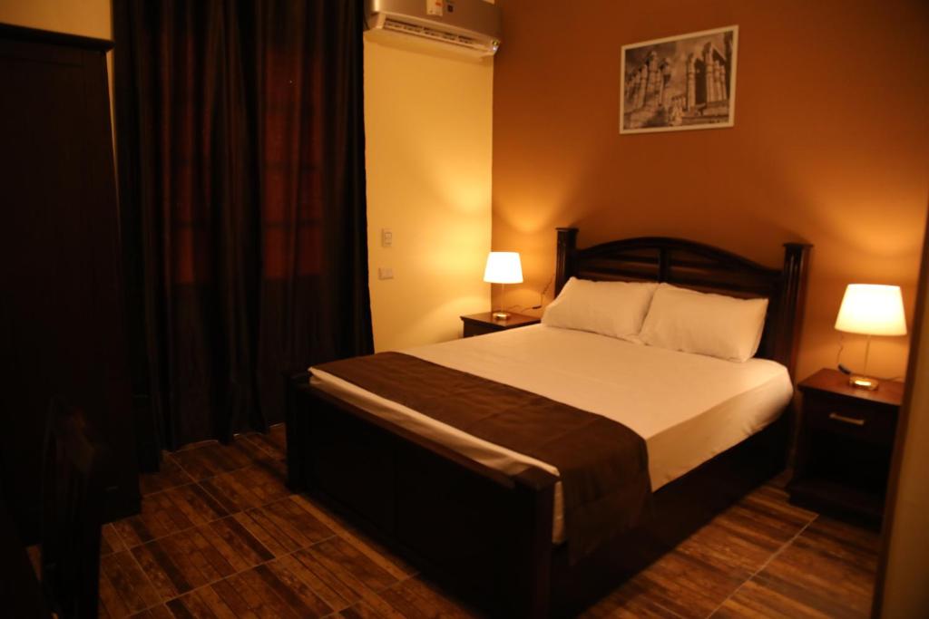 um quarto com uma cama com duas mesas de cabeceira e dois candeeiros em Gresham Hotel no Cairo