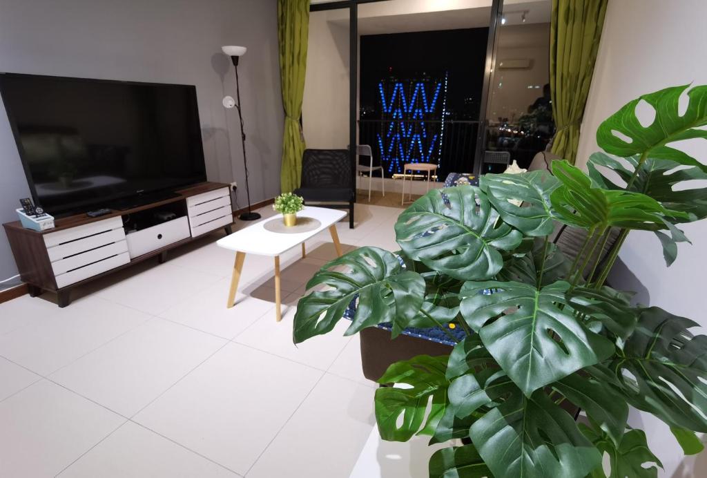 a living room with a flat screen tv and a plant at LM HomeyA 3 BdRm Coastline View condo for 4-14 Pax with Netflix & Coway Water Purifier in Tanjong Tokong