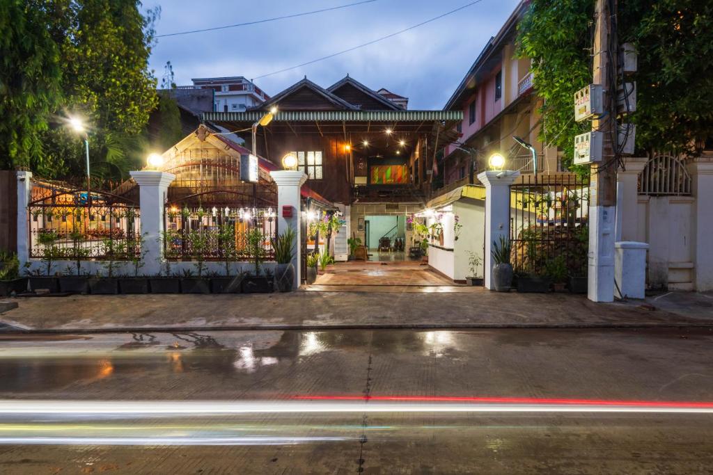 uma rua da cidade à noite com um portão e carros em Happy Heng Heang Guesthouse em Siem Reap