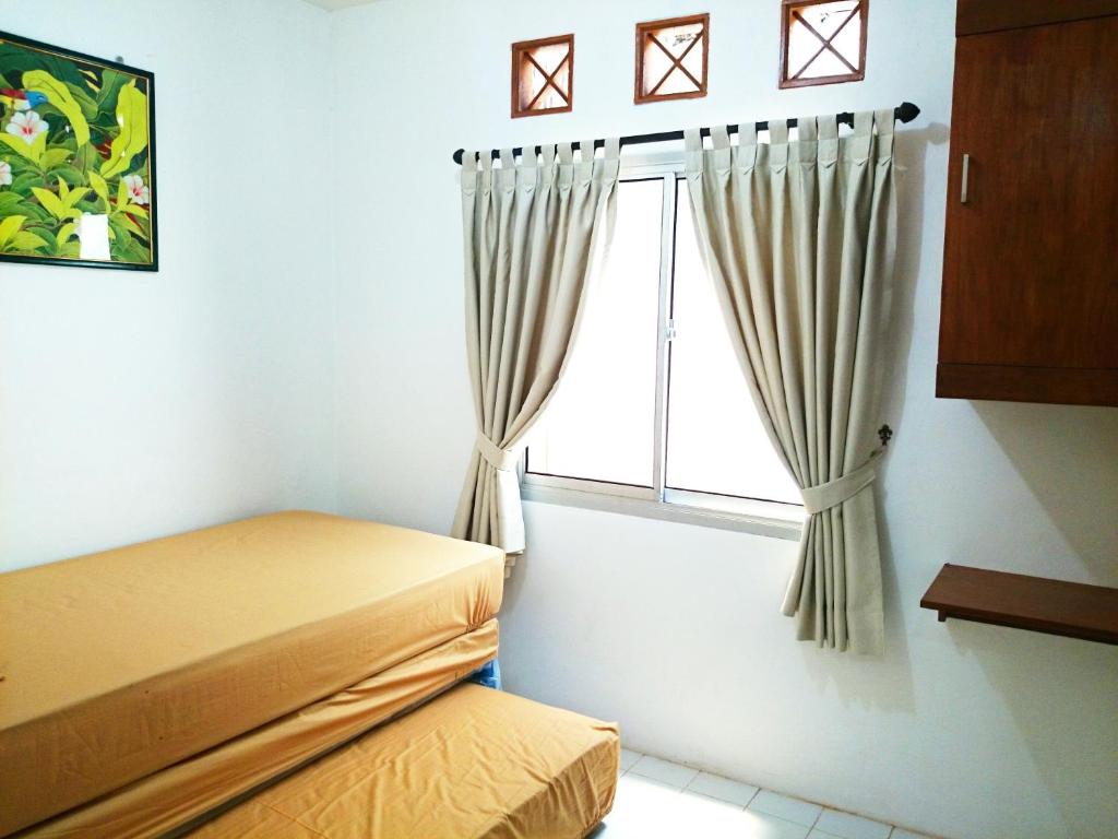 a bedroom with a bed and a window with curtains at Hostel Bogor in Bogor