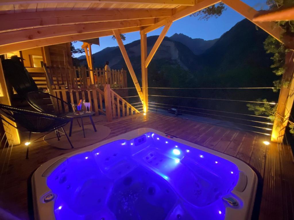 a hot tub on a deck with a view of the mountains at Chalet l'Empreinte in Saint-Étienne-de-Tinée