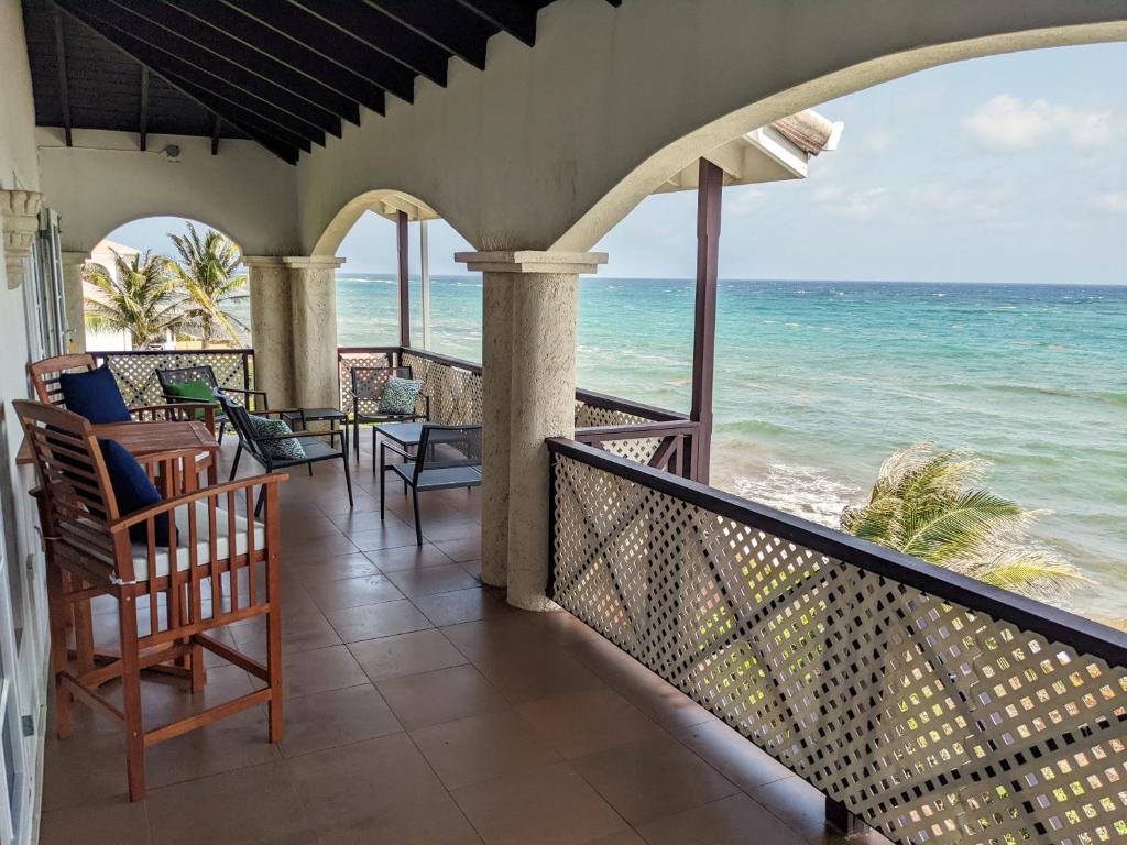 a balcony with chairs and a view of the ocean at Breezy Ocean Front Condo Close to The Best Beaches in Christ Church
