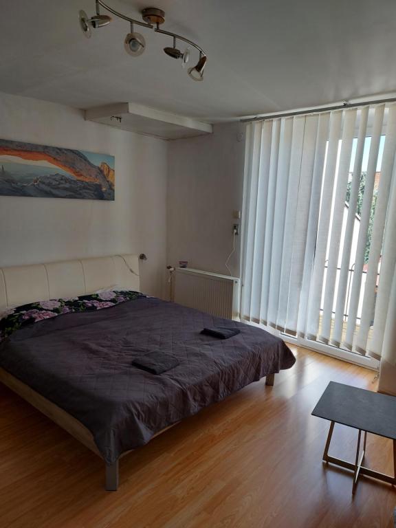 a bedroom with a large bed and large windows at Picolo apartmany in Levoča