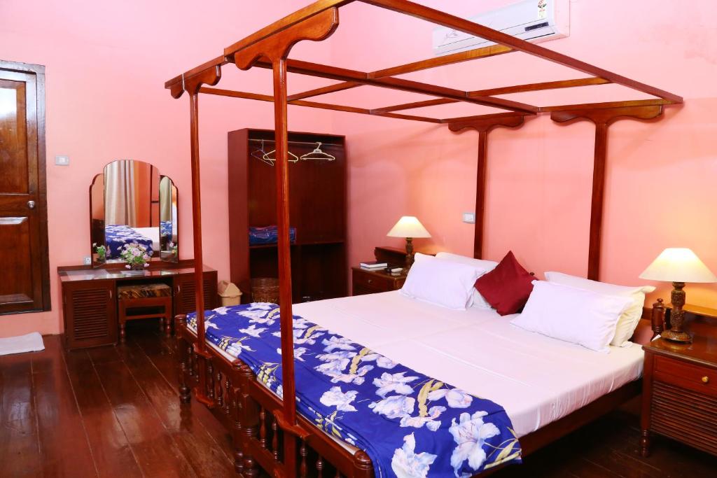 a bedroom with a four poster bed with a canopy at Chiramel Residency in Cochin