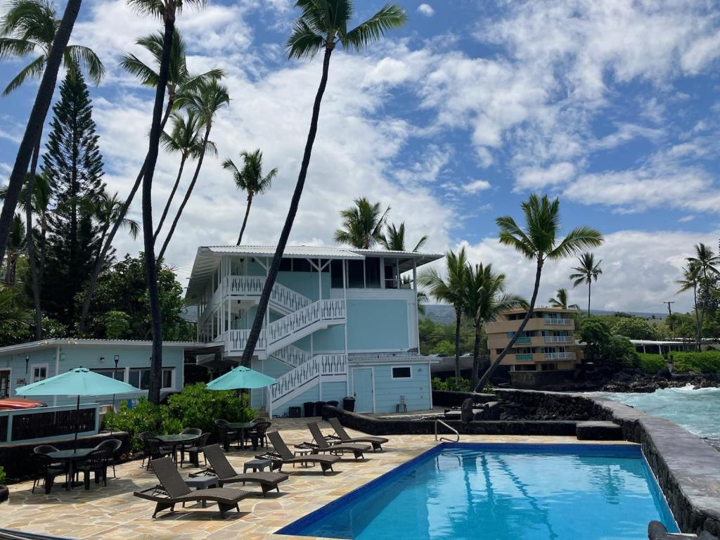 un complejo con piscina, sillas y palmeras en Kona Tiki Hotel, en Kailua-Kona