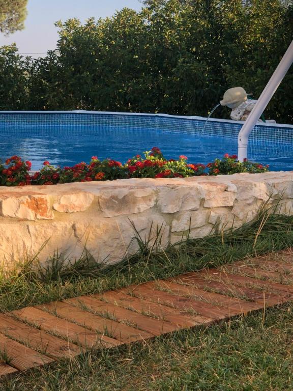a retaining wall with flowers next to a swimming pool at Villa Messerà in Martina Franca