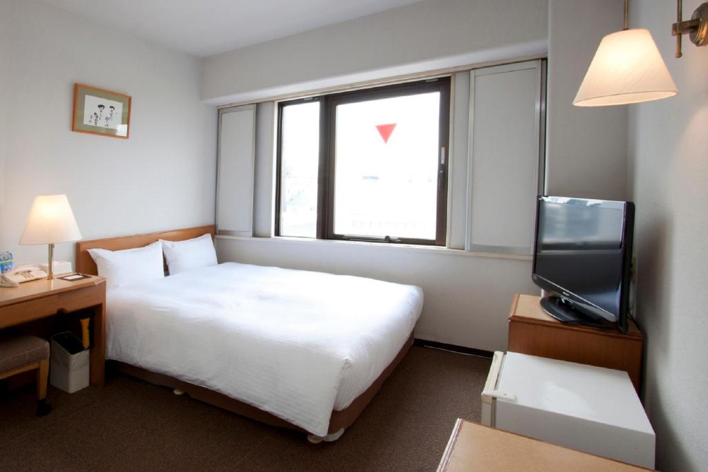 a hotel room with a bed and a television at Smile Hotel Sugamo in Tokyo