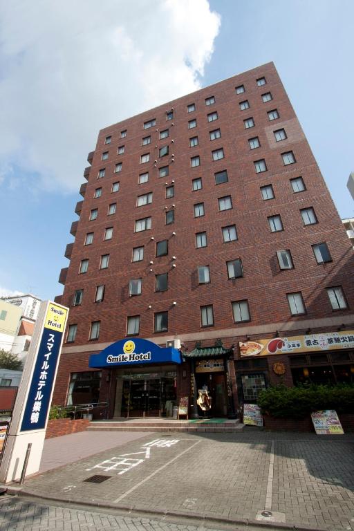 a large brick building with a sign in front of it at Smile Hotel Sugamo in Tokyo