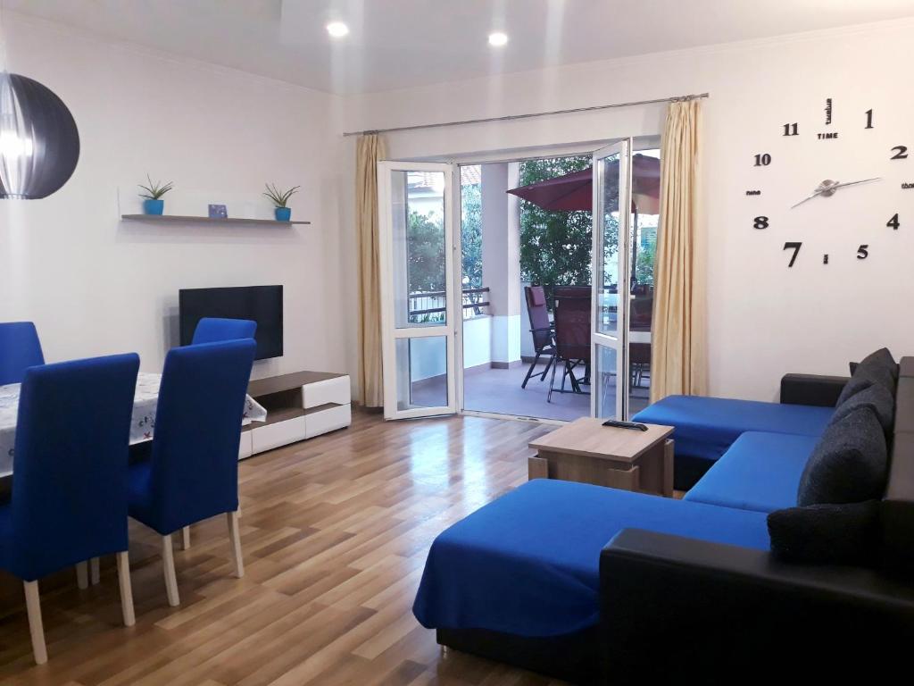 ein Wohnzimmer mit einem blauen Sofa und einem Tisch in der Unterkunft Apartmani i soba Andrijasevic in Makarska