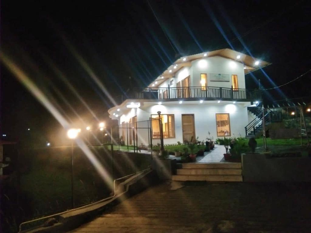 una gran casa blanca con luces por la noche en Memento Vivere, en Kanatal