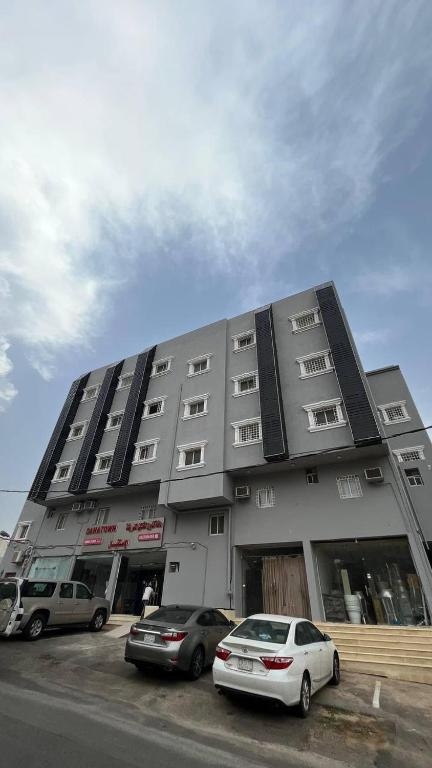 a building with two cars parked in front of it at دانة تاون للوحدات السكنية "يوجد إيجار شهري" in Abha