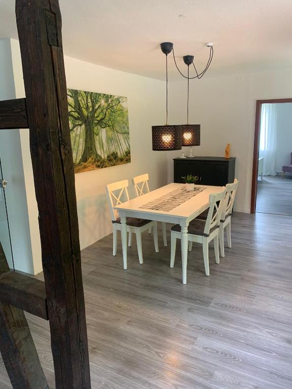 a dining room with a white table and chairs at Ferienwohnung an der Oker in Altenau