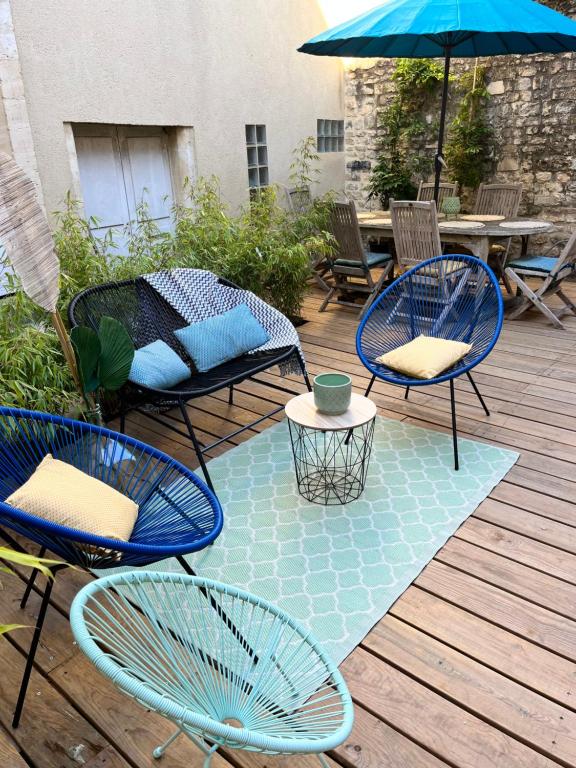 patio z krzesłami, stołem i parasolem w obiekcie SAMANDINE HOME w mieście Bayeux