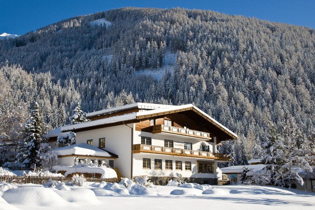 uma casa na neve em frente a uma montanha em Ferienhaus Alpina em Kals am Großglockner