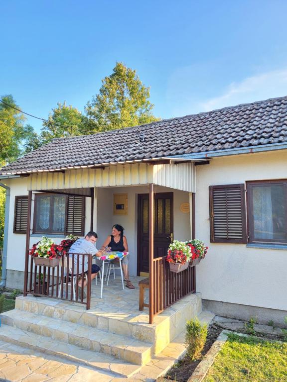 duas pessoas sentadas no alpendre de uma casa em Venera em Kosjerić