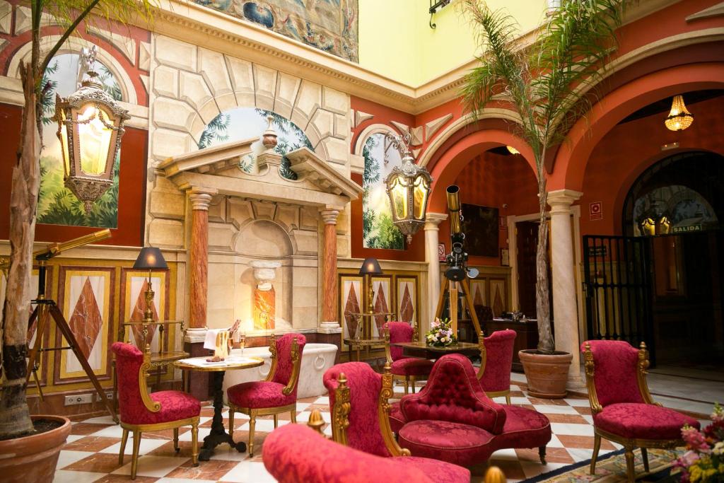 a lobby with red chairs and a table in a building at Hotel Ateneo Sevilla in Seville