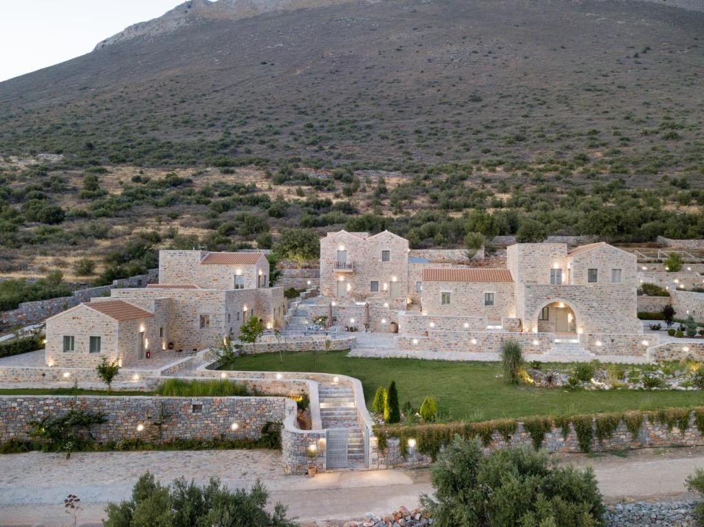 アレオポリにあるArmantanis Luxury Suitesの山を背景にした大きな石造りの家屋の空中風景