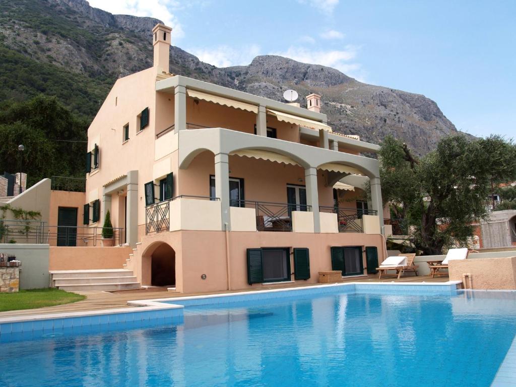 a house with a swimming pool in front of a mountain at Villa Iris in Barbati