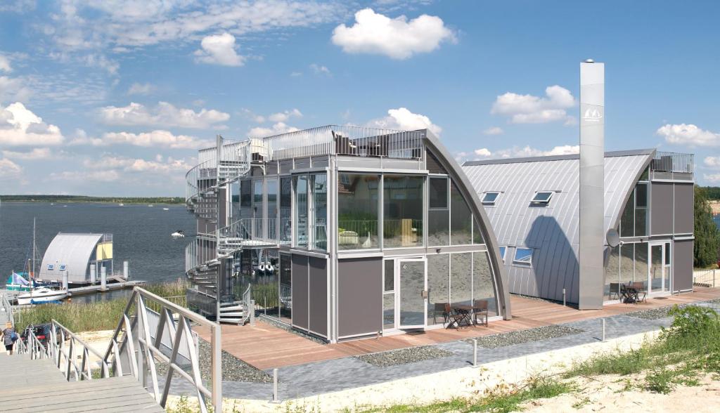 ein Haus auf einem Dock neben einem Wasserkörper in der Unterkunft Open-Water-Resort in Geierswalde