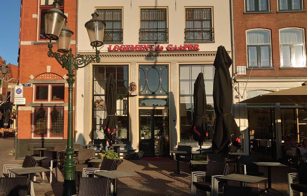 ein Restaurant mit Tischen und Sonnenschirmen vor einem Gebäude in der Unterkunft Hotel de Gaaper in Amersfoort