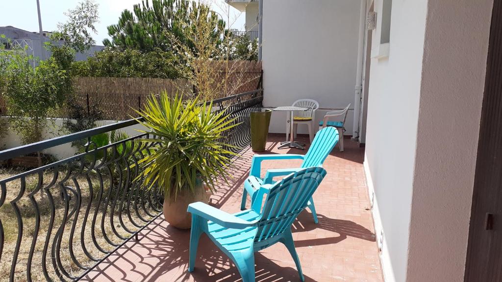 2 sillas azules sentadas en un balcón con plantas en Bel appartement avec grande terrasse ensoleillée et jardin, en Perpiñán