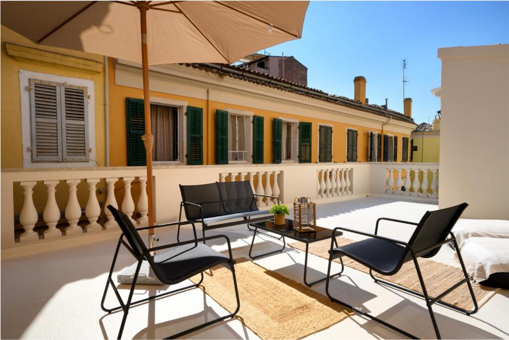 - une terrasse avec des chaises et un parasol dans un bâtiment dans l'établissement The In Town Apartment - With a Private Terrace, à Corfou