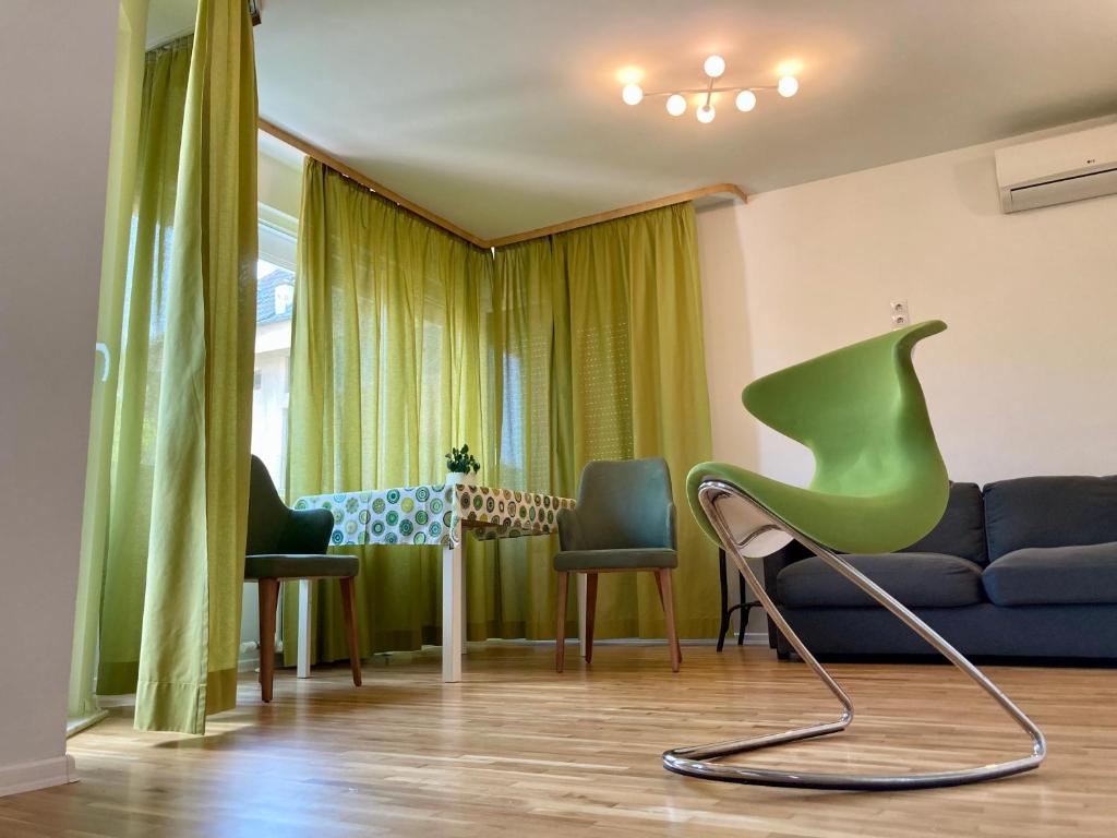a living room with a green chair and a couch at Orfey Apartment in Sofia