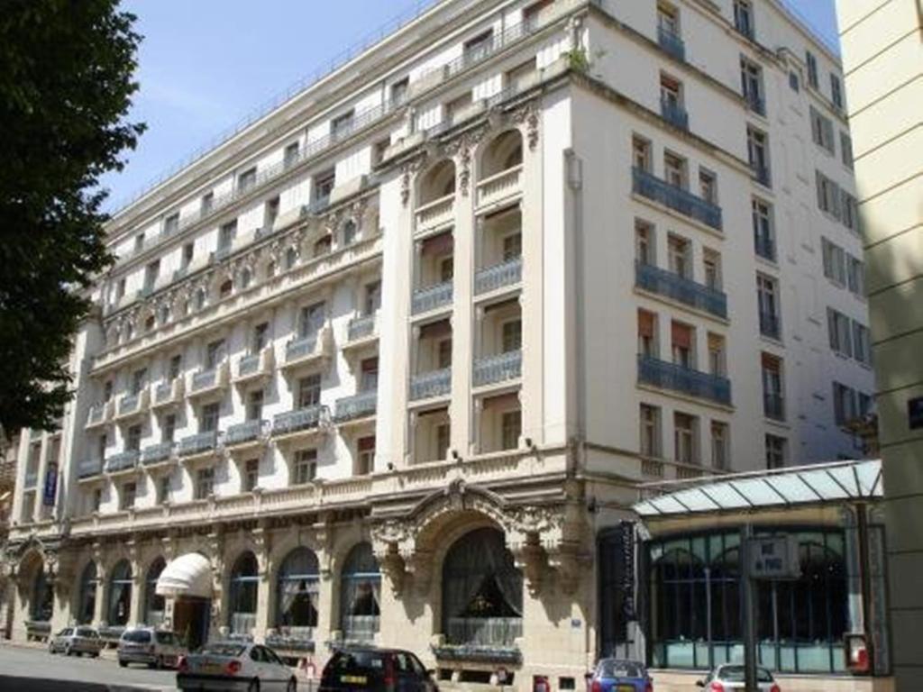 un gran edificio blanco con coches estacionados frente a él en Hôtel Aletti Palace, en Vichy