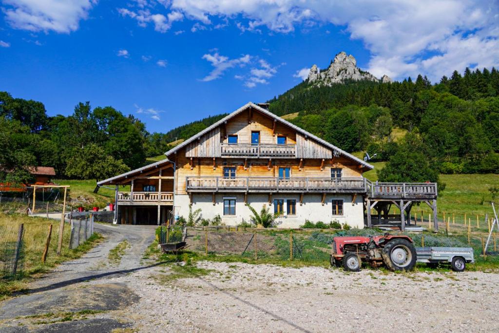 ein großes Holzhaus mit einem Traktor davor in der Unterkunft La Ferme De L'âne Rouge 7 nuits minimum in Bernex