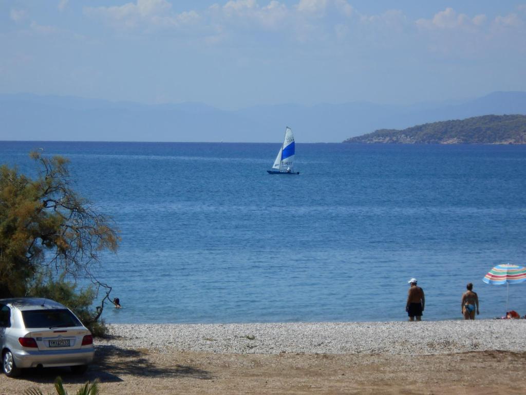 un velero en el agua con dos personas en una playa en Blue Beach, en Porto Heli