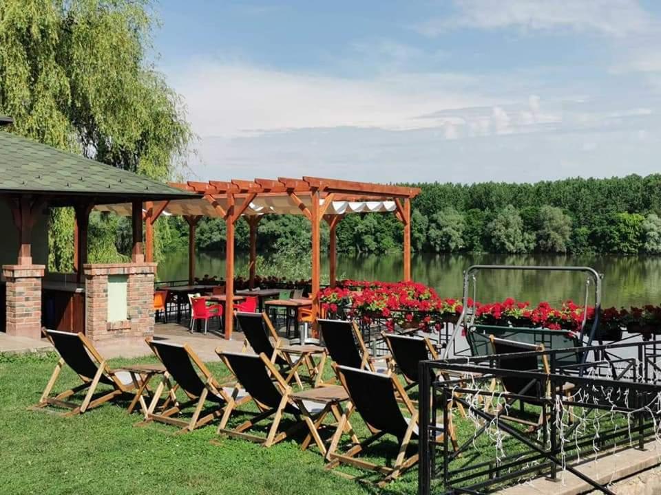 um grupo de cadeiras e um gazebo ao lado de um lago em Vila Odmor na Dunavu em Beočin