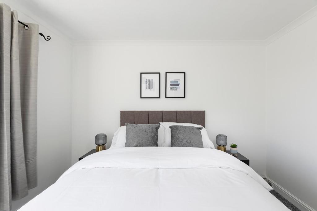 um quarto com uma grande cama branca e 2 almofadas em Parkside House em Stevenage