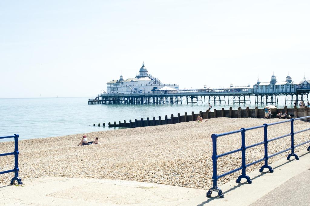 a beach with a pier and people laying on the sand at Shore View Hotel in Eastbourne