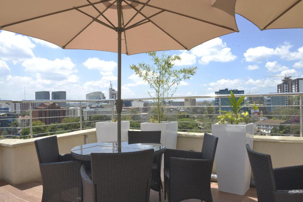 patio con tavolo, sedie e ombrellone di La Maison Royale a Nairobi