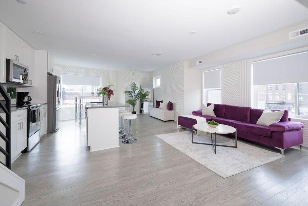 a living room with a purple couch and a kitchen at Montgomery condo in Philadelphia