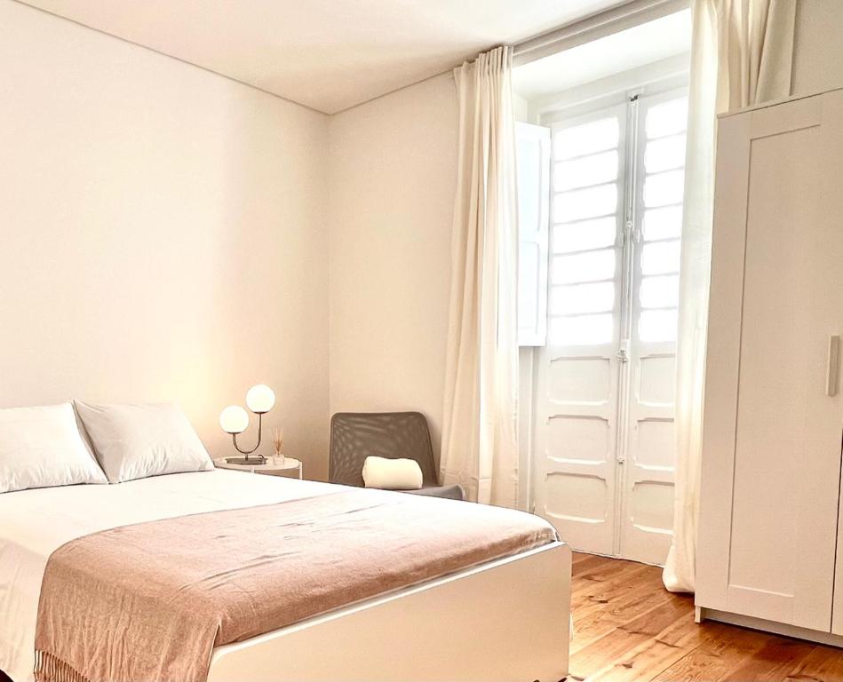 リスボンにあるPortugália Apartmentsのベッドルーム1室(ベッド1台、椅子、窓付)