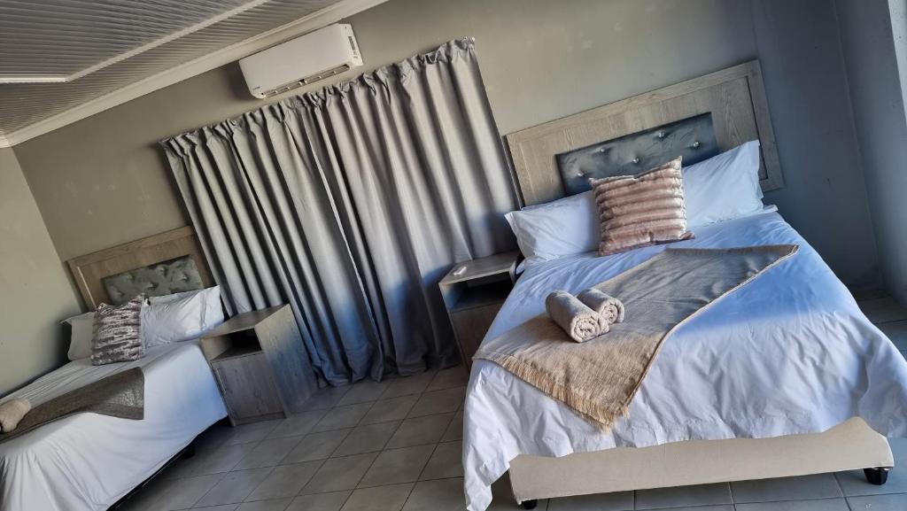 een slaapkamer met 2 bedden en een raam met gordijnen bij The Unit Party House in eNyalungu