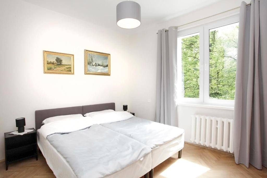 a white bedroom with a bed and a window at Apartament Ada in Sopot