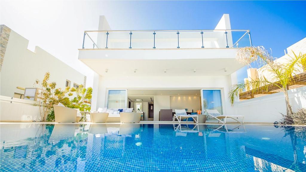 a swimming pool with chairs and a house at Protaras Holiday Villa 100 in Protaras