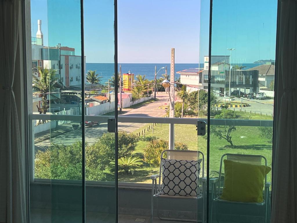 una ventana con una silla y vistas al océano en Desfrute de Mariscal a 150 M da Praia - V6, en Bombinhas